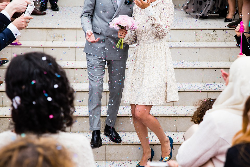 Guests throw confetti at a wedding couple on the courthouse steps