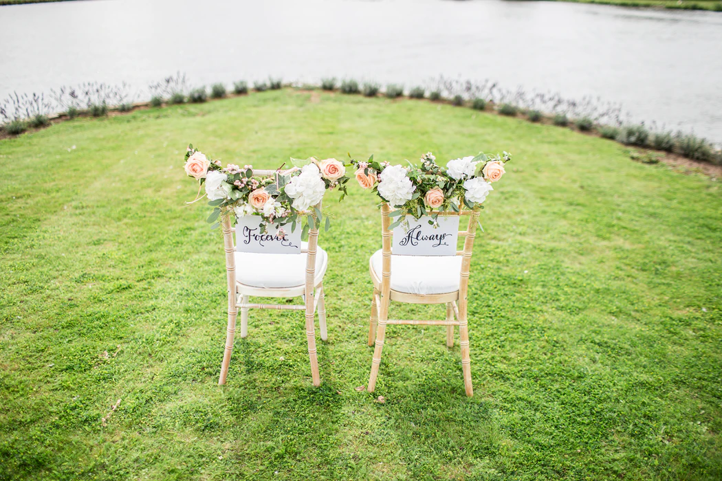 Wedding words: two ceremony chairs decorated flowers and signs that read "forever" and "always"