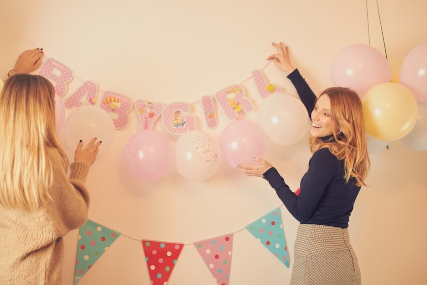 Baby shower decorations: people decorating the wall with balloons and party banners