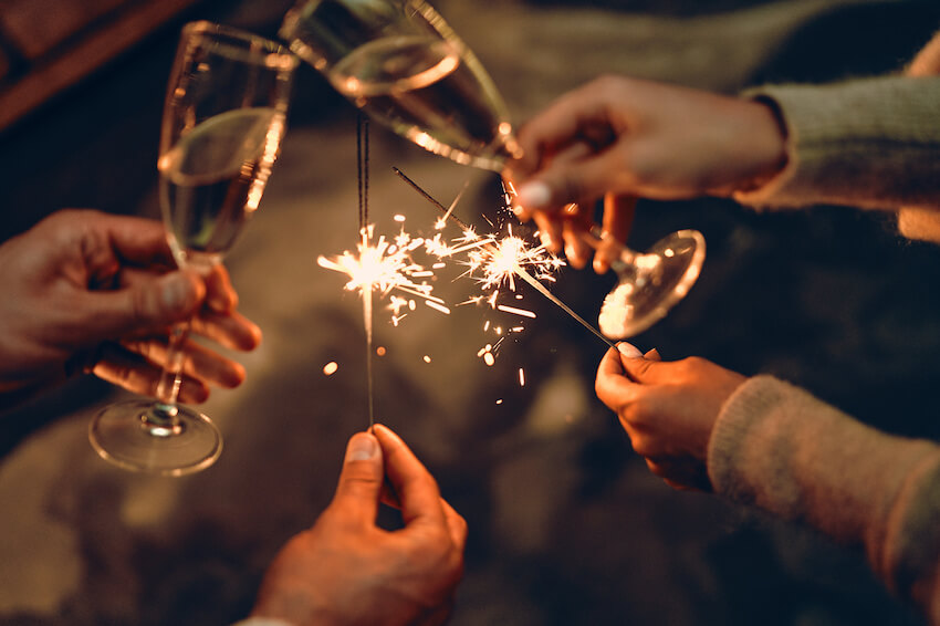 Happy New Year wishes for friends: people having a toast while holding some sparklers