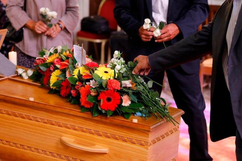 Funeral service announcement: people placing flowers on a coffin