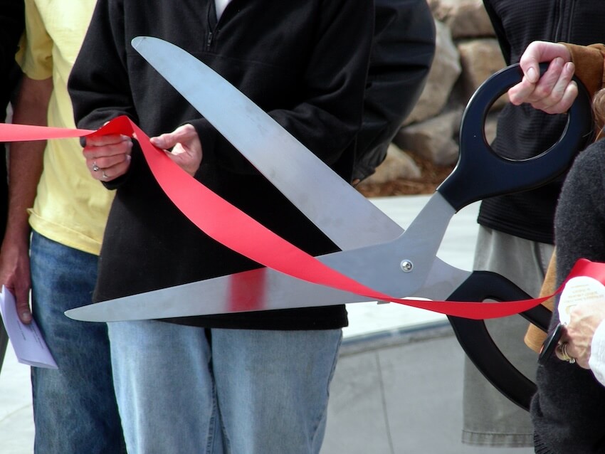 Person cutting a ribbon using a giant pair of scissors