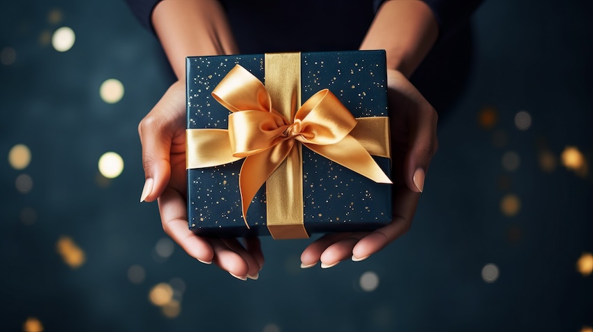 Happy New Year gift: person holding a gift with a golden ribbon
