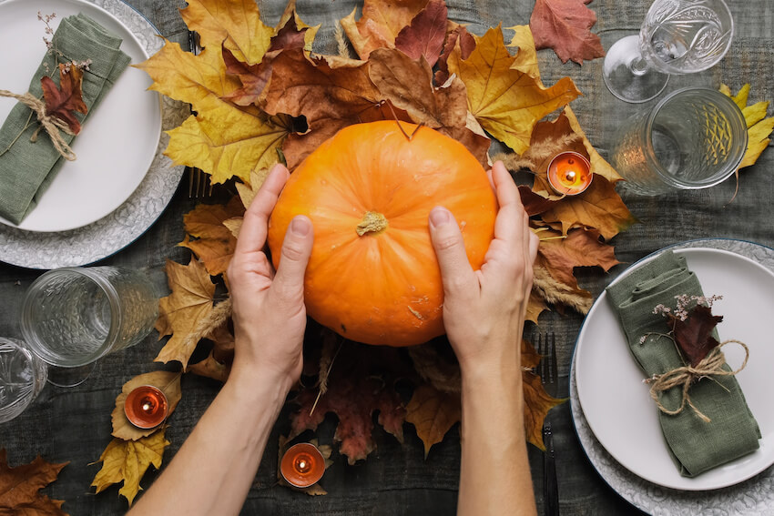 Person placing a pumpkin on a table