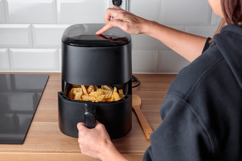 Person using an air fryer to cook french fries