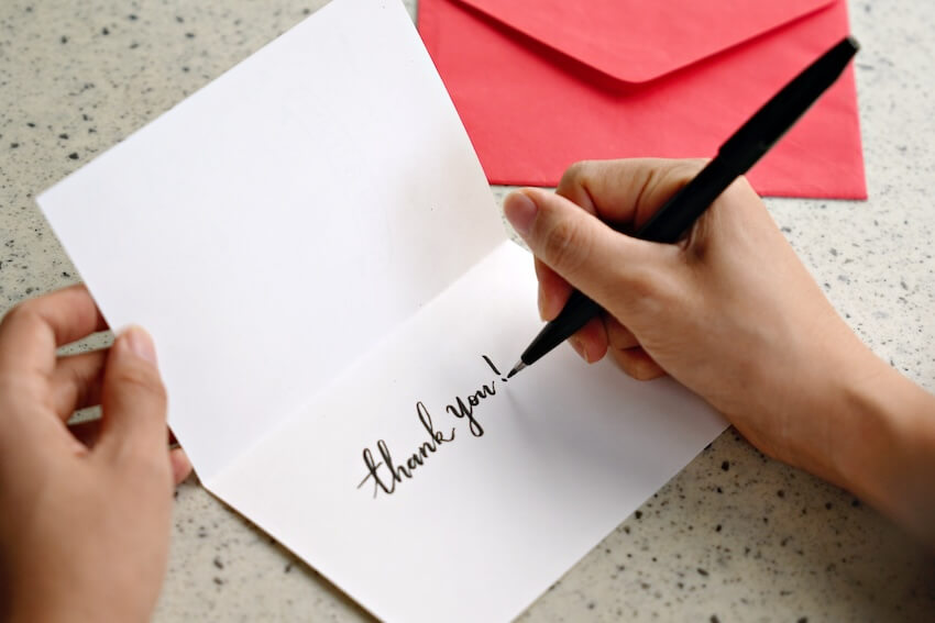 Person writing a thank you card