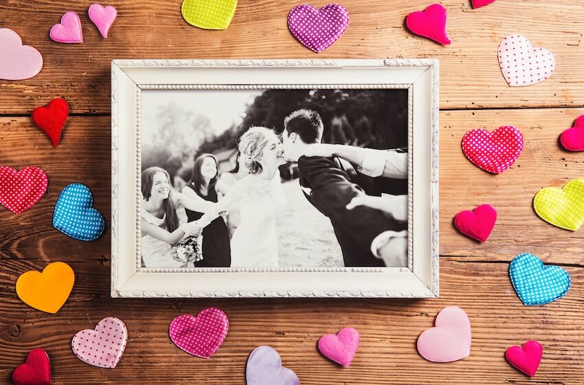 Picture frame of a married couple kissing with colorful hearts surrounding it
