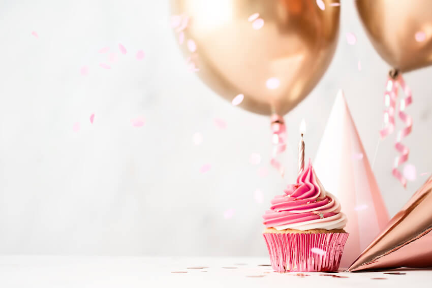 Pink cupcake with balloons on the background