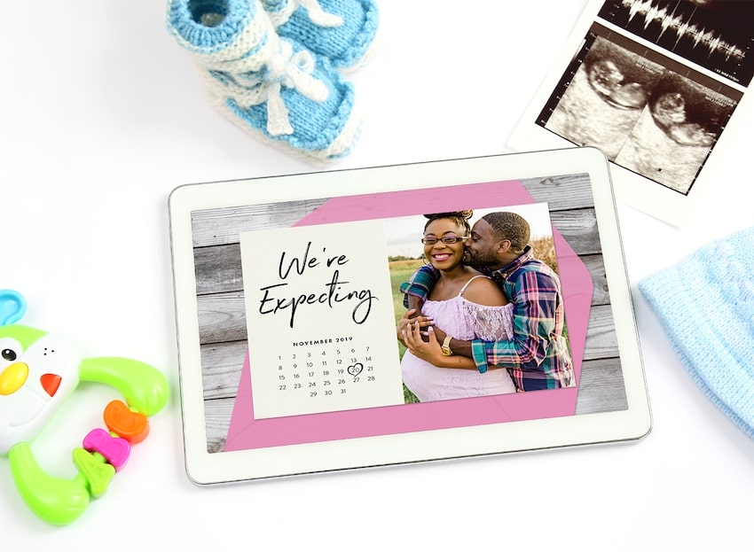 Digital pregnancy announcement: pregnancy announcement on a tablet screen and some baby stuff