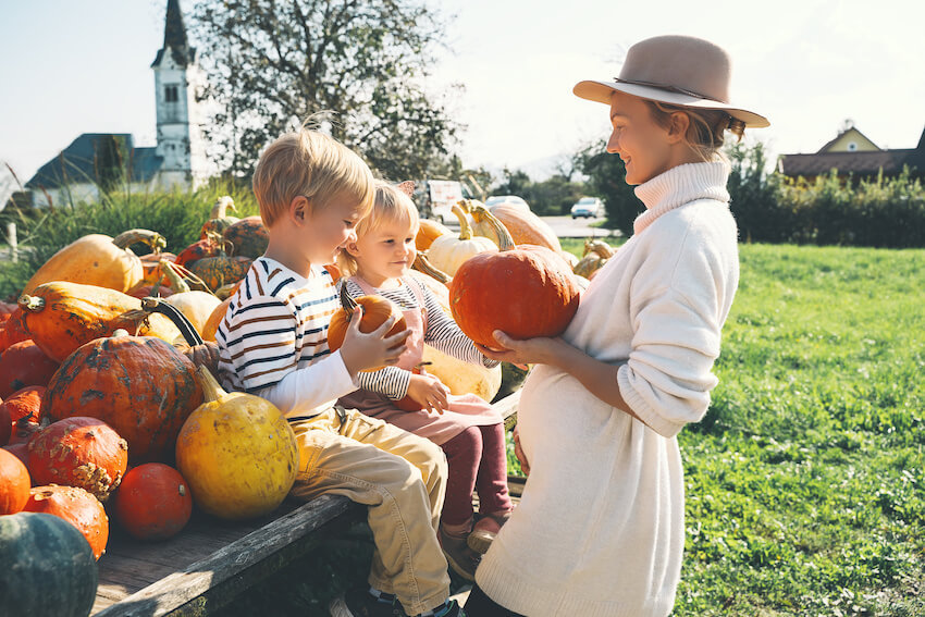 Outdoor baby shower: pregnant mother and her kids holding pumpkins