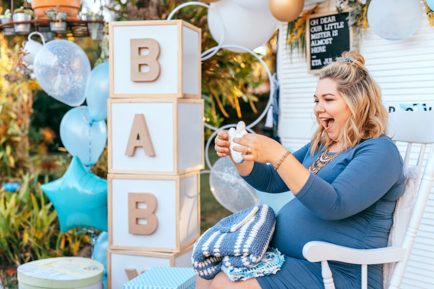 Baby shower checklist: pregnant woman opening gifts at her baby shower