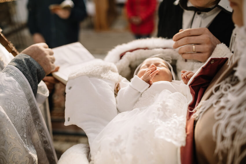 Baby’s baptism: priest baptizing a sleeping baby