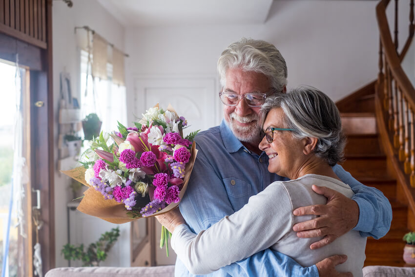 Senior couple holding a bouquet while hugging each other