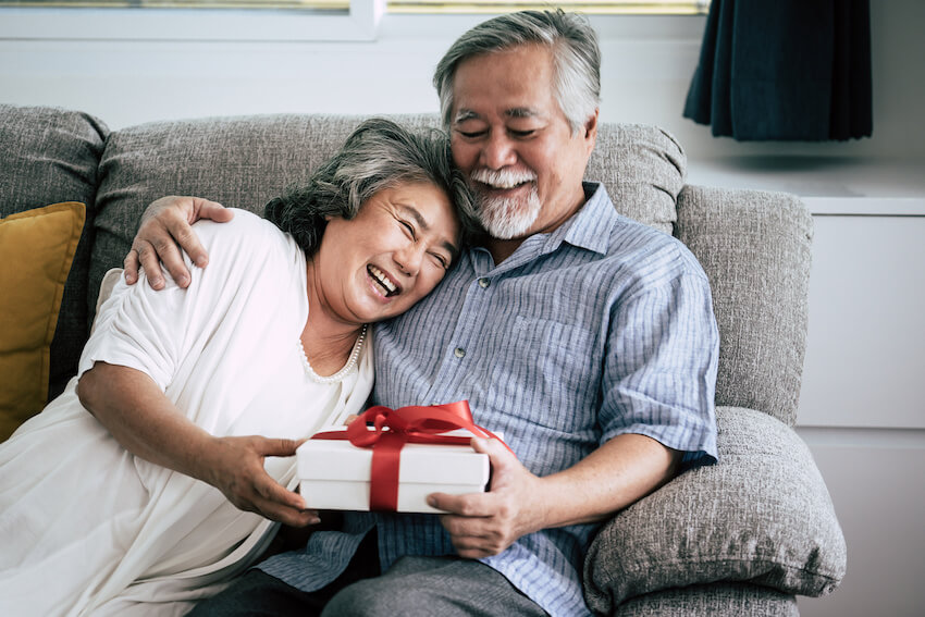 Senior couple holding a gift while sitting on a couch