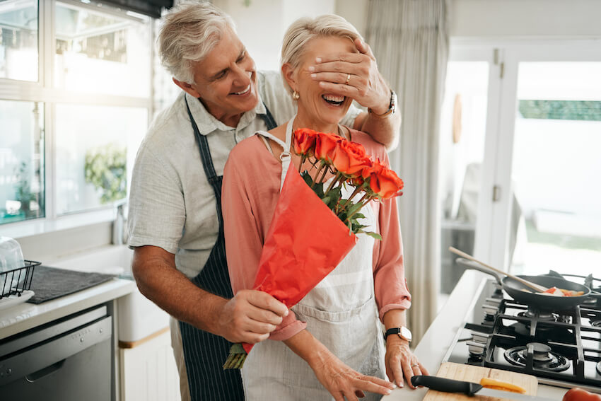 Senior man surprising his wife with a bouquet of flowers