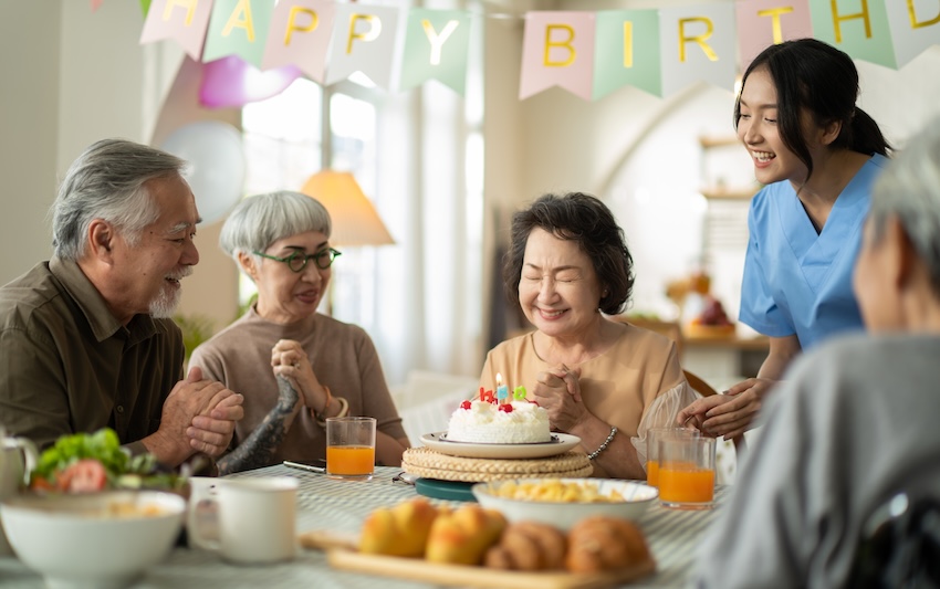 75th birthday ideas: senior woman celebrating her birthday at a retirement home with friends and a nurse