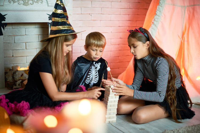 Halloween party themes: siblings wearing Halloween costumes and playing Jenga