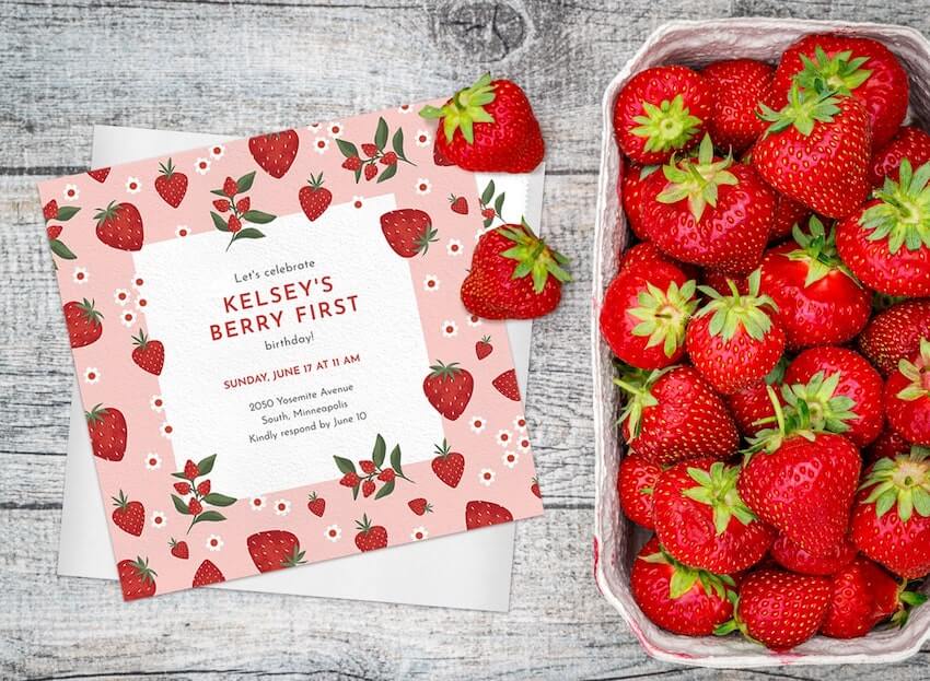 Berry first birthday: strawberry themed invitation and a bowl of strawberries on the side