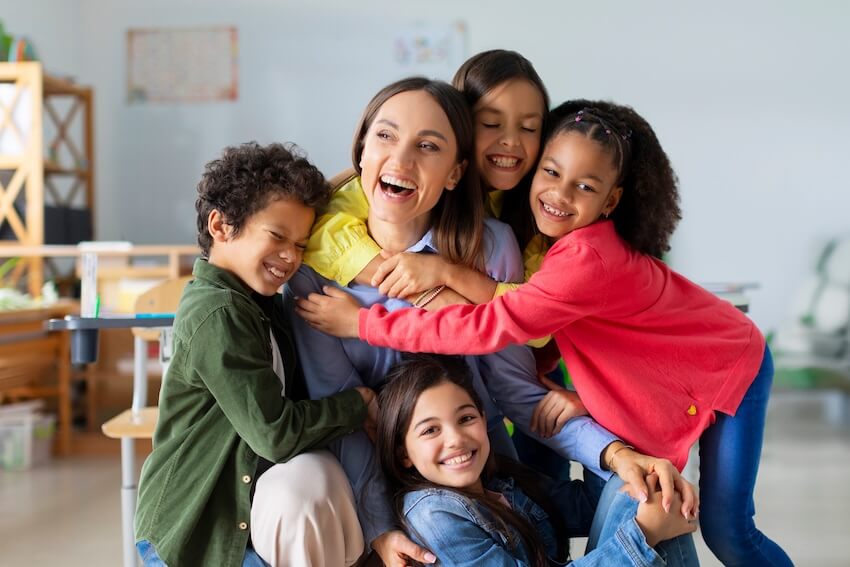 Teacher birthday: students happily hugging their teacher