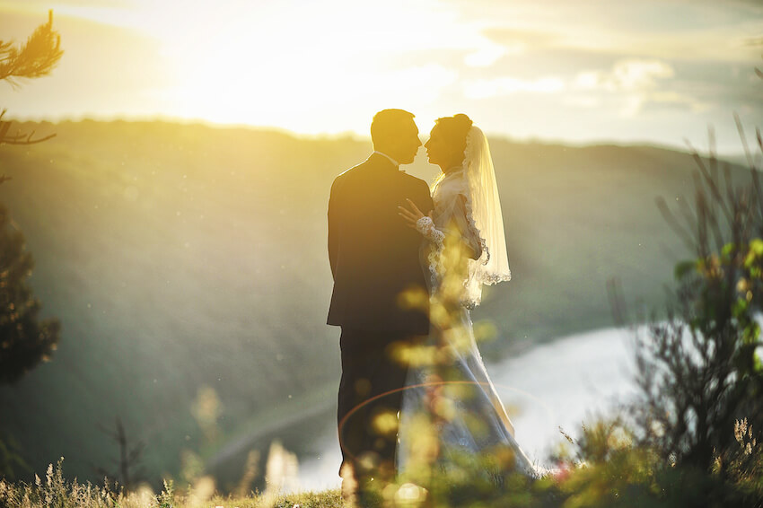 Bride and groom kissing under the sunset