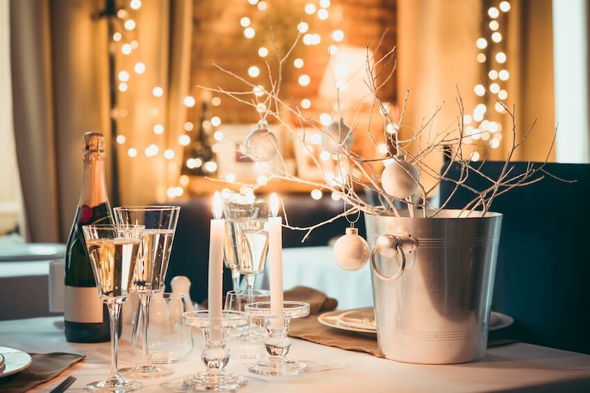 New Years Eve decoration ideas: table setting with a bottle of wine, 2 candles, and wine glasses