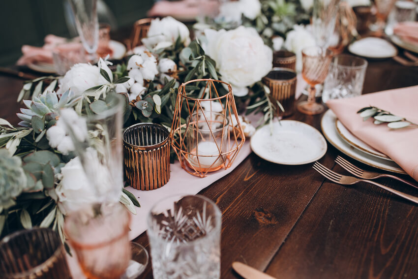 Rehearsal dinner decorations: table setting with glasses, plates, candles, and flowers