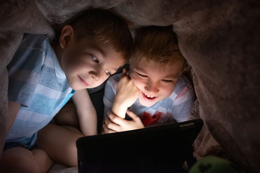 two boys watching a movie on a tablet