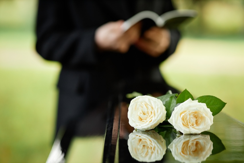 Funeral service announcement: closeup of two white roses on a coffin