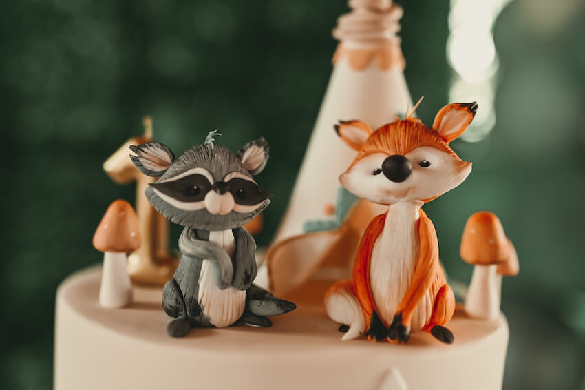 Woodland baby shower: two fox figures sitting on a cake