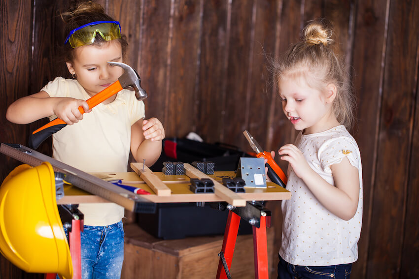 Construction birthday party: two girls using a hammer and a pair of pliers