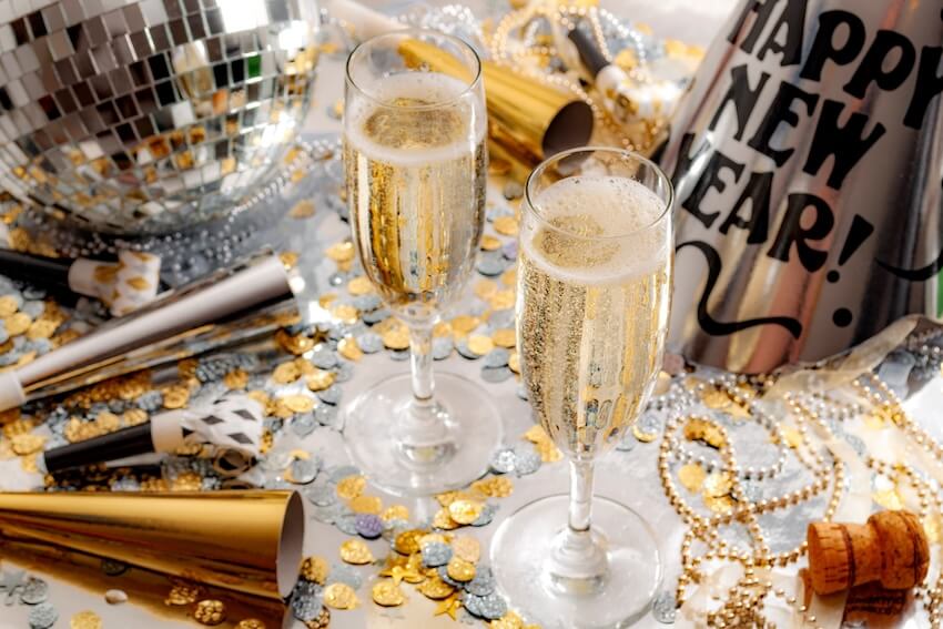 New Years Eve decoration ideas: two glasses of champagne, party trumpets, and a party hat on a table