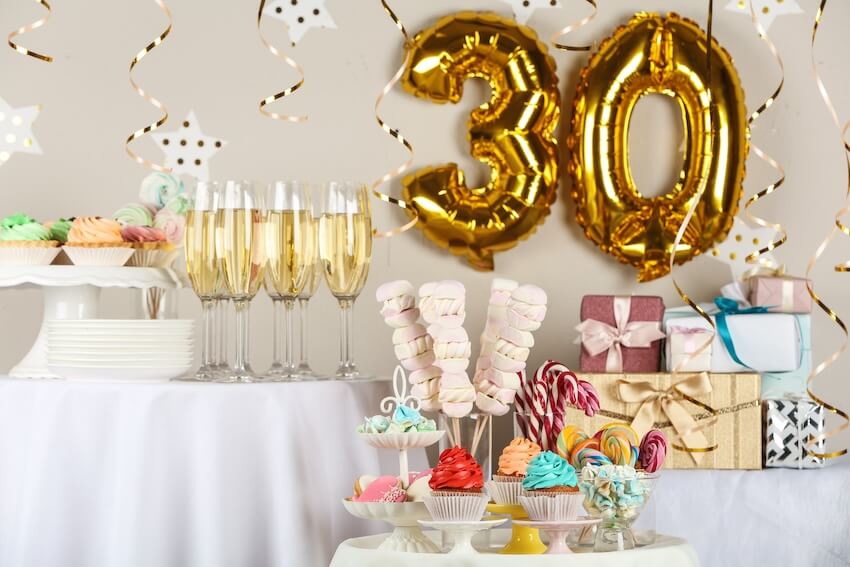 30th birthday invitations: various desserts, drinks, and gifts on a table