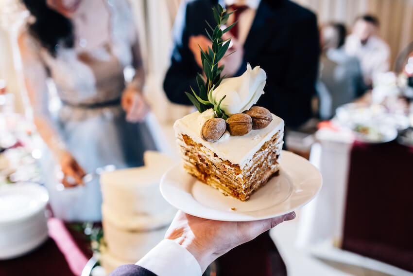 Waiter serving a slice of cake with nuts on top
