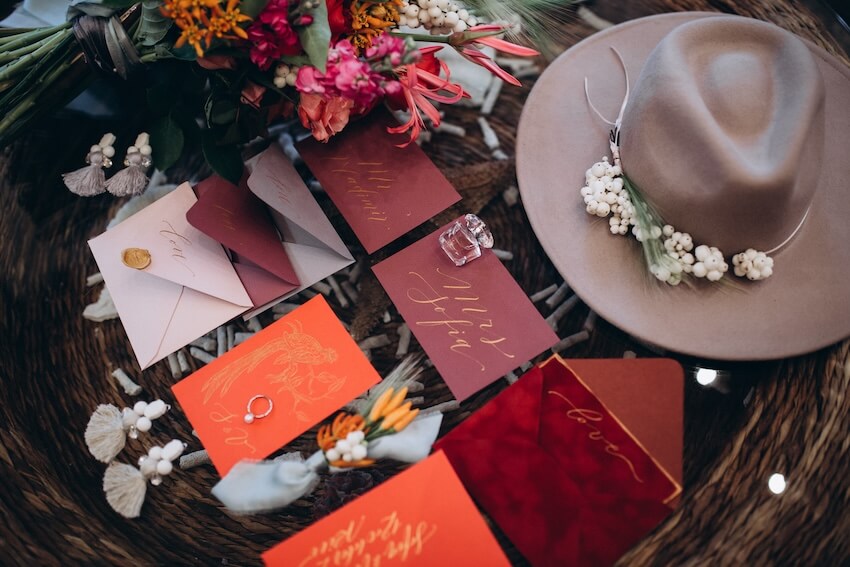 Wedding invitations, a hat, and a bouquet of flowers on a table