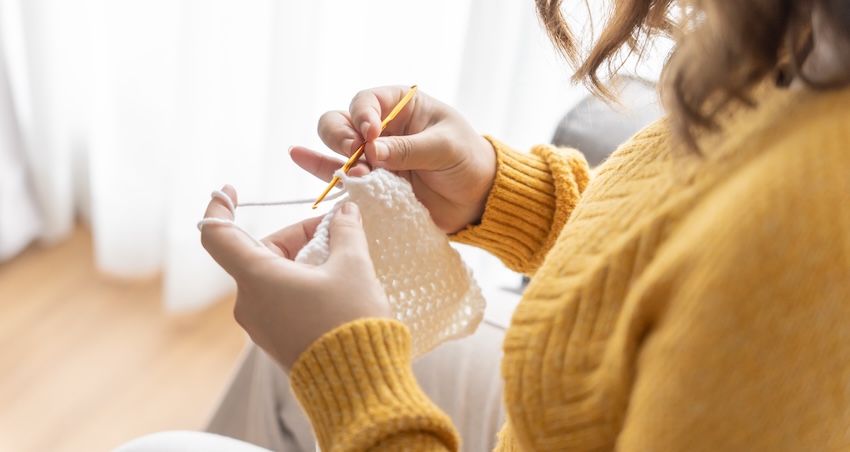 DIY baby shower gifts: woman crocheting at home
