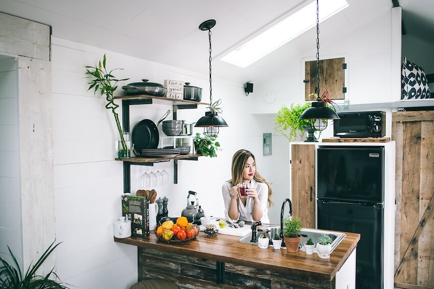 Housewarming invitation: woman drinking a cup of tea in her kitchen