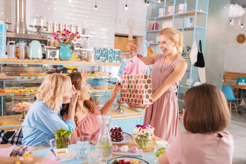 When to have a baby shower: woman giving a gift to her pregnant friend