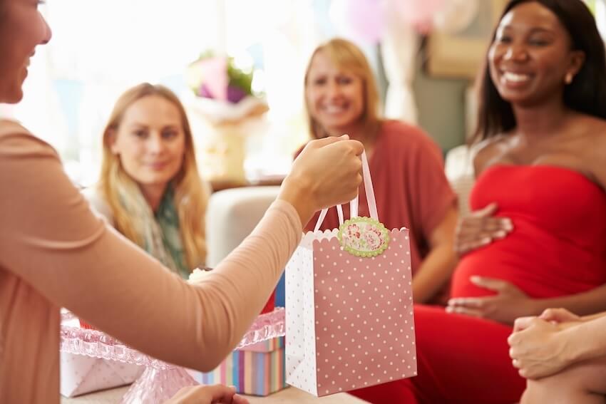 Baby sprinkle gift ideas: woman handing a gift to her friend