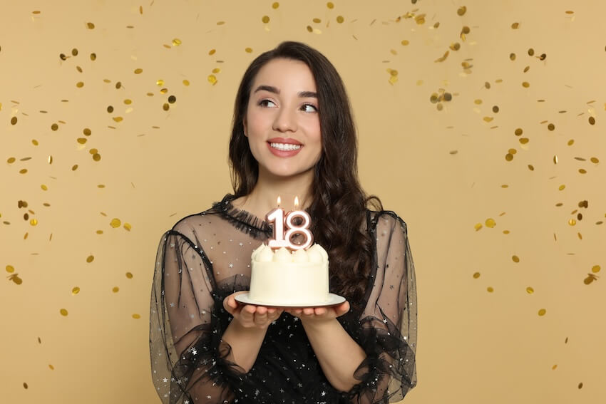 Woman happily holding her cake with confetti in the background