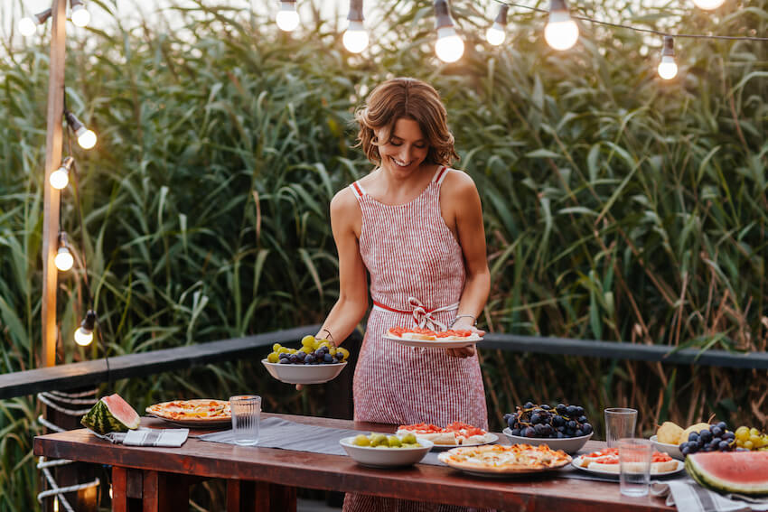 Housewarming party ideas: woman happily holding plates of food