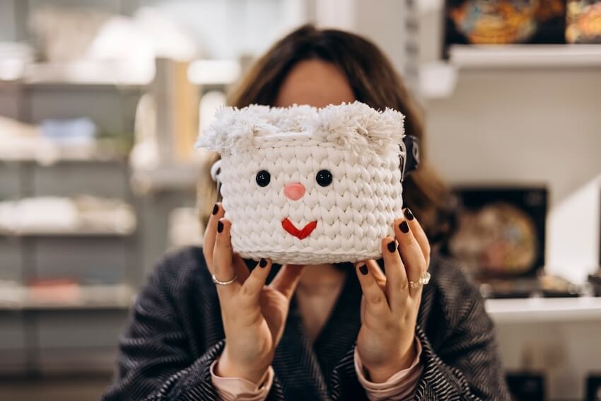 30th birthday gift ideas: woman holding a crochet basket with a smiley face design on it