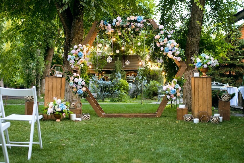 Backyard wedding: wooden arch with flowers and hanging lights