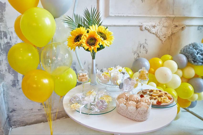 Sunflower baby shower: yellow balloons, sunflowers, and food on a table